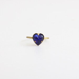 May include: A gold ring with a dark blue heart-shaped gemstone.