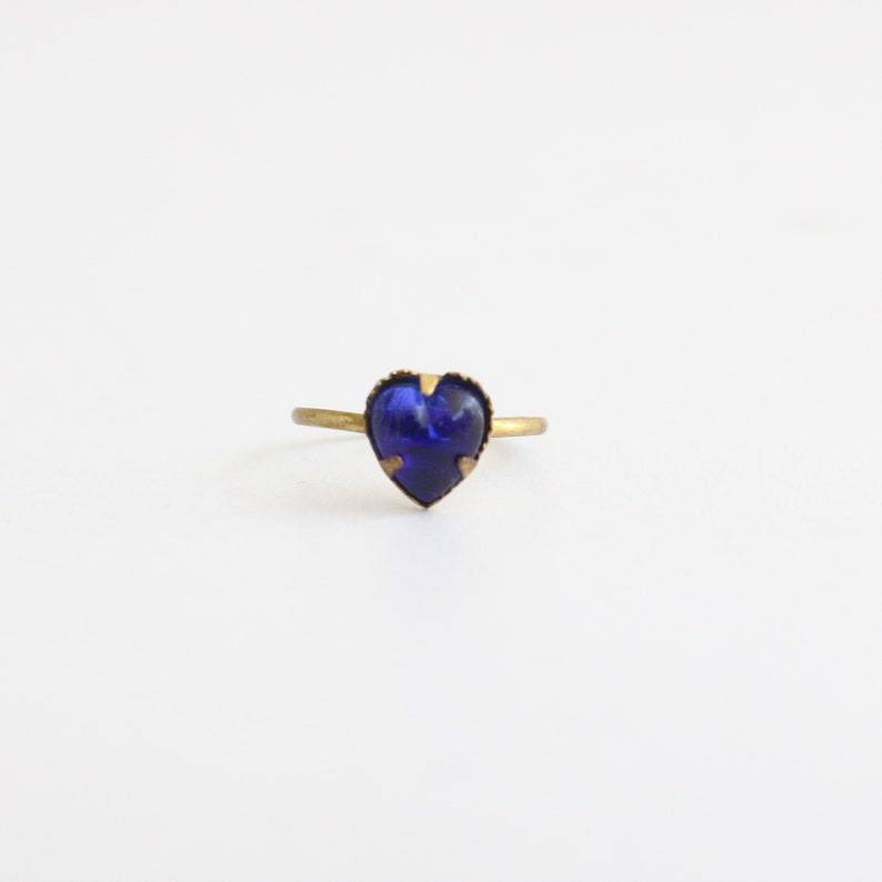 May include: A gold ring with a dark blue heart-shaped gemstone.