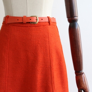 May include: A bright orange skirt with a thin, orange leather belt and a gold buckle.