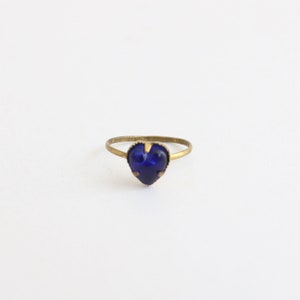 May include: A gold ring with a blue heart-shaped gemstone.