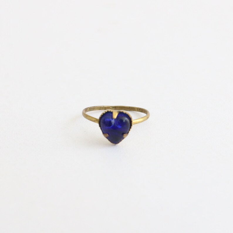 May include: A gold ring with a blue heart-shaped gemstone.