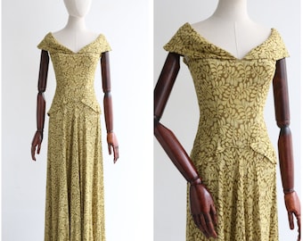 May include: A long, green dress with a floral pattern. The dress has a V-neckline and a fitted bodice. The skirt is full and flowing.