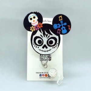 Puede incluir: Un carrete de insignia de brillo blanco y negro con una imagen de dibujos animados de una niña con cara de calavera y una corona de flores. El carrete tiene dos orejas de Mickey Mouse de brillo blanco y negro con una calavera y notas musicales. El texto "with love" está en la oreja con las notas musicales. El carrete está unido a una tarjeta blanca con el texto "FOLLOW ME ON SO" e iconos de redes sociales.