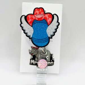 May include: A badge reel featuring a blue and silver design with a red cowboy hat and wings. The badge reel has a pink glitter accent and a rhino graphic with the text "Mr. Rhino".