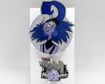 May include: A glittery badge reel featuring a cartoon character with a blue and purple color scheme. The character has a large blue headpiece and a dark blue collar. Below the character is a gray rhino with the text "Mr. Rhino".