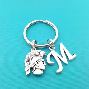 May include: Silver keychain with a Roman warrior helmet charm and a letter M charm.