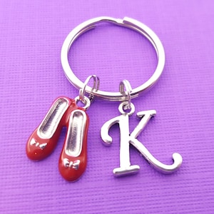 May include: A silver key chain with two red ruby slipper charms and a silver charm with the letter K.