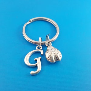 May include: Silver keyring with a silver letter G charm and a silver ladybug charm.