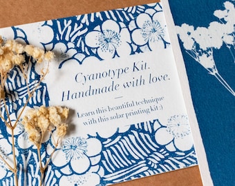 Könnte beinhalten: Eine weiße Karte mit einem blauen Blumenmuster und dem Text "Cyanotype Kit. Handmade with love. Learn this beautiful technique with this solar printing kit:)"