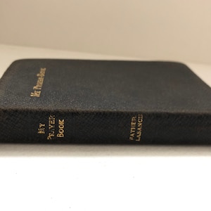 May include: A black leather-bound book with gold lettering on the spine. The title is "My Prayer Book" and the author is "Father Lasance".