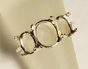 May include: Silver ring setting with three oval-shaped bezels. The ring is designed to hold three gemstones.