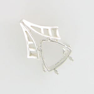 May include: A silver-colored jewelry setting with an open, triangular design. The setting has a geometric shape with a series of bars and supports, designed to hold a gemstone. The piece is likely for a pendant or earring.