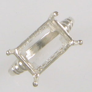 May include: Silver ring setting with an emerald-shaped bezel. The setting is designed to hold a gemstone.