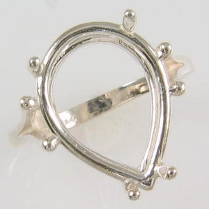 May include: Silver ring setting with a pear-shaped bezel for a gemstone.