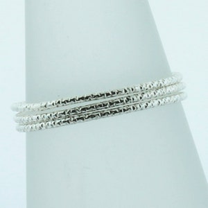 May include: Three silver bangles with a textured, diamond-like pattern.