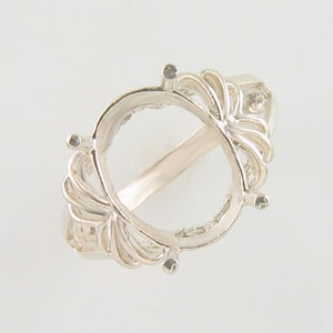 May include: Silver ring setting with an oval shaped bezel and delicate filigree details.