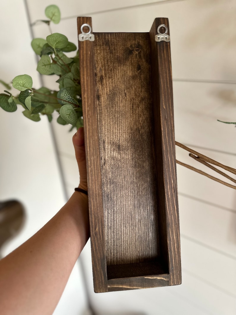 Two handmade rustic wooden wall sconces with a dark, rich wood finish. Wood color is customizable. Each planter holds a vibrant faux eucalyptus plant. Minimalist yet elegant design making this piece perfect for a rustic, farmhouse or bohemian style