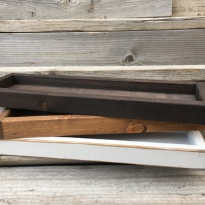 May include: Three wooden trays stacked on top of each other. The top tray is dark brown, the middle tray is light brown, and the bottom tray is white.