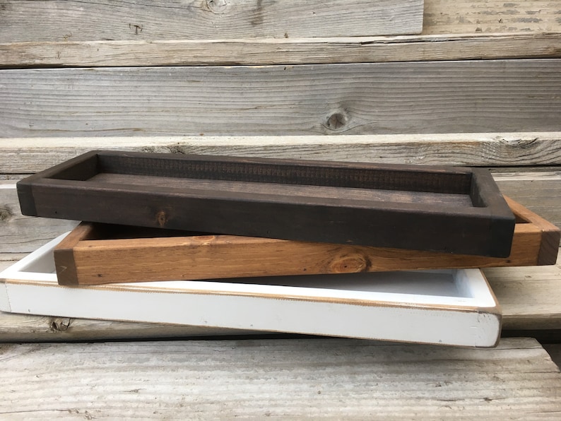 May include: Three wooden trays stacked on top of each other. The top tray is dark brown, the middle tray is light brown, and the bottom tray is white.