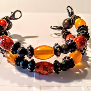 May include: A double-strand bracelet with orange, red, and black beads. The bracelet has a clasp closure.