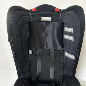 Peut inclure: Siège auto noir pour enfant avec appui-tête et dossier rembourrés. Le siège est doté de sangles noires, d'une housse noire satinée et du logo "infasecure". Le siège porte une étiquette avec le texte "WARNING".