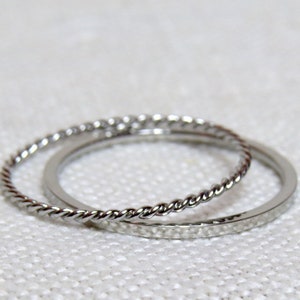 May include: Two silver rings, one with a twisted design and the other with a hammered texture.
