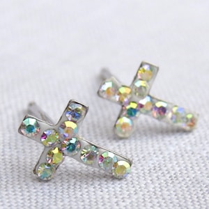 May include: A pair of silver cross earrings with iridescent rhinestones.
