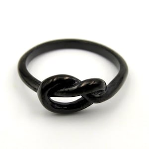 May include: A black knot ring with a simple, elegant design. The ring is made of metal and has a smooth, polished finish.