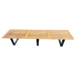 May include: A mid-century modern bench with a slatted wooden top and black metal legs. The bench is rectangular and features a natural wood finish, showcasing the grain of the wood. The legs are angled and provide sturdy support.