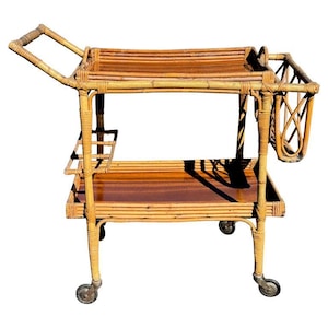 May include: A vintage bamboo bar cart with a wooden top and two shelves. The cart has four wheels and a handle. It is made of natural materials and has a rustic look.
