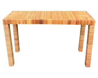 May include: A rectangular table constructed from layered, light brown bamboo strips. The surface features a linear pattern with chevron-style corners, supported by four straight, matching legs that extend to the floor in a uniform design.