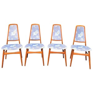 May include: Four mid-century modern chairs with light wood frames and blue patterned upholstery. The chairs have a tall back and a curved seat, with a design that evokes a retro aesthetic. The chairs are set against a white background.