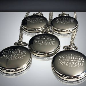 May include: Five silver pocket watches with chains, each engraved with a name and the date 04/14/18. The names are Charles, Father of the Groom, Spencer, Sam Groomsman, Willie Groomsman, and William Groomsman.