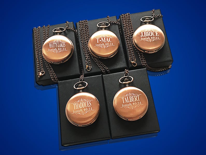 May include: Five antique-style pocket watches with chains, each engraved with a name and the scripture Isaiah 40:31. The watches are displayed on black velvet boxes.