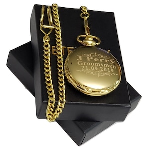 K&ouml;nnte beinhalten: Goldene Taschenuhr mit einer goldenen Kette in einer schwarzen Box. Das Zifferblatt der Uhr ist mit dem Text "J Perry Groomsmen 21.09.2019" graviert.