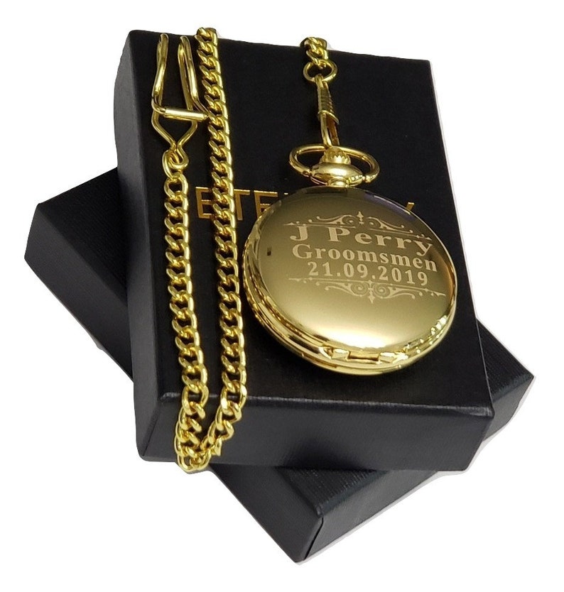 K&ouml;nnte beinhalten: Goldene Taschenuhr mit einer goldenen Kette in einer schwarzen Box. Das Zifferblatt der Uhr ist mit dem Text "J Perry Groomsmen 21.09.2019" graviert.
