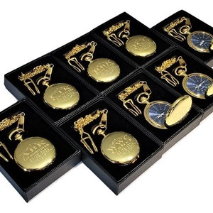 May include: Ten gold pocket watches in black boxes with chains. Each watch has a different inscription on the front.