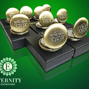 May include: A collection of gold pocket watches with personalized engravings. Each watch is displayed in a black box with a white interior. The watches feature different engravings, including "Groomsman", "Father of the Bride", and "Curley".