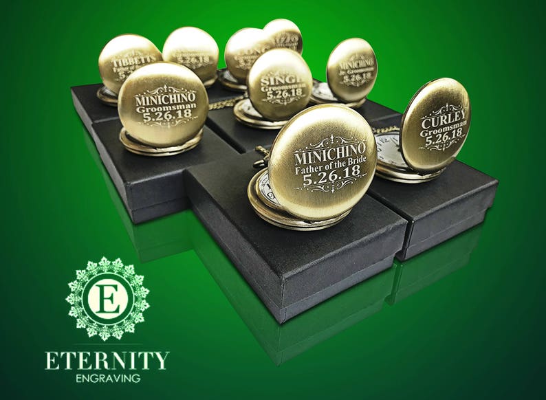 May include: A collection of gold pocket watches with personalized engravings. Each watch is displayed in a black box with a white interior. The watches feature different engravings, including "Groomsman", "Father of the Bride", and "Curley".