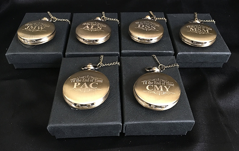 K&ouml;nnte beinhalten: Sechs goldene Taschenuhren mit Ketten in schwarzen Boxen. Jede Uhr hat eine andere Inschrift: "Til the End of Time JMW", "Til the End of Time ALS", "Til the End of Time DSS", "Til the End of Time MSM", "Til the End of Time PAC" und "Til the End of Time CMY".