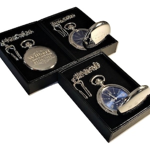 K&ouml;nnte beinhalten: Drei silberne Taschenuhren in schwarzen Samtboxen. Die Uhren haben eine silberne Kette und einen silbernen Anh&auml;nger. Eine Uhr hat ein blaues Zifferblatt mit r&ouml;mischen Ziffern und den Text "Eternity" auf dem Zifferblatt. Die beiden anderen Uhren haben ein silbernes Zifferblatt mit einer gravierten Botschaft. Eine Uhr sagt "Wilbert, ein Herz zum Sch&auml;tzen Freund 01/16/2021".