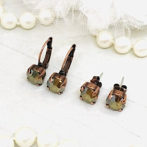 May include: A set of three earrings with a copper finish and a light brown crystal. The earrings are available in two styles: a hoop and a stud.