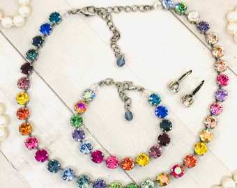 May include: A rainbow crystal necklace, bracelet and earrings set. The necklace and bracelet feature a rainbow of colours, including red, orange, yellow, green, blue, indigo and violet. The earrings are small and feature a single crystal each.