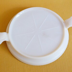 Peut inclure: Plat de service en verre de lait blanc avec deux poignées. Le plat a un centre circulaire avec un motif en relief de huit rayons qui rayonnent du centre.