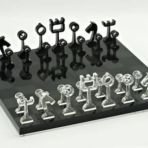 May include: A black and white chess set with abstract, geometric pieces. The chessboard is black with white squares. The pieces are made of clear acrylic.