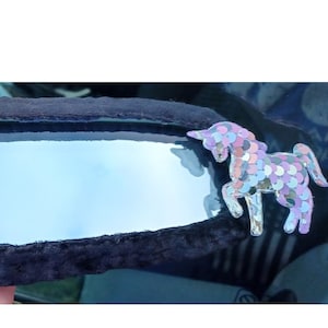May include: Black car rearview mirror cover with a pink heart and a sparkly unicorn design.