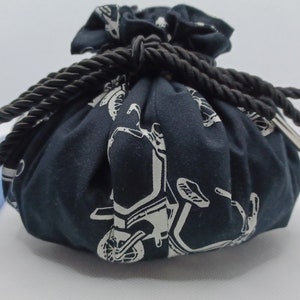 May include: A black drawstring bag with a white design of motorcycles. The bag is made of fabric and has a black rope drawstring.