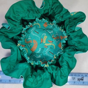 May include: A green fabric sensory bin with a colorful printed lining featuring the words "Repens", "Portia", "Elliare", "Ridium", "Wing", "Peliare", "Usoine", and "Rensd".