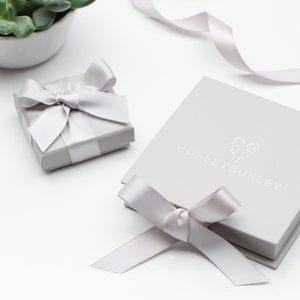 May include: Two gray gift boxes with white satin ribbon bows. The larger box has the text "HURLEY EURLY" printed on the top.