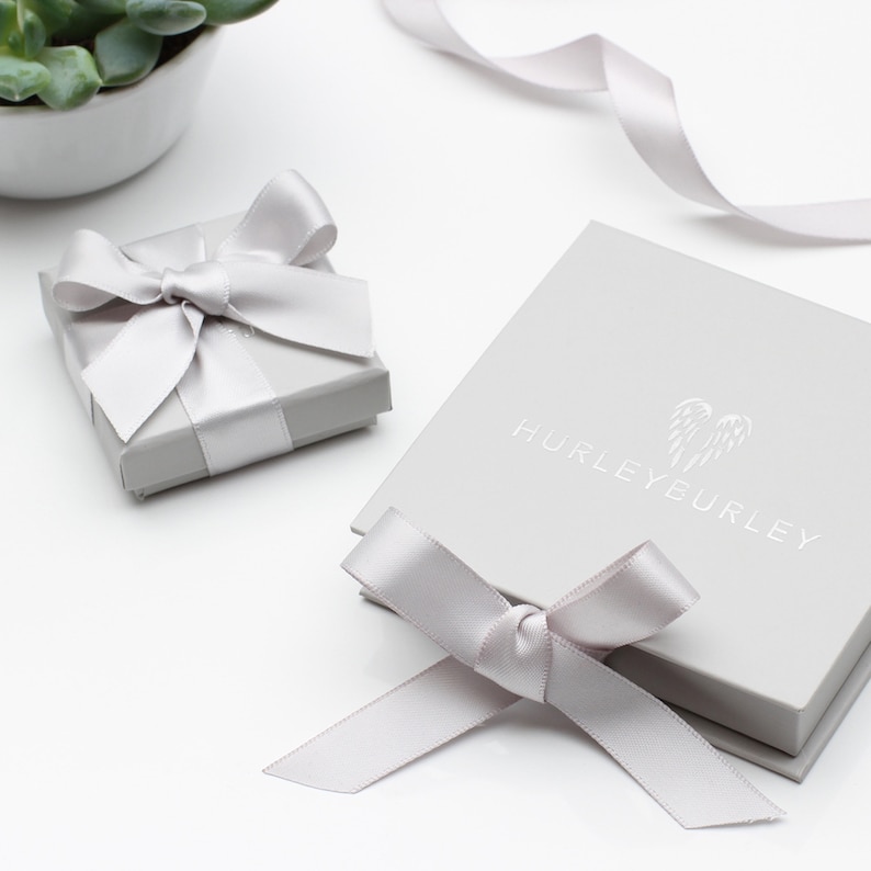 May include: Two gray gift boxes with white satin ribbon bows. The larger box has the text "HURLEY EURLY" printed on the top.